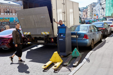 Men load an ATM into van on city street.