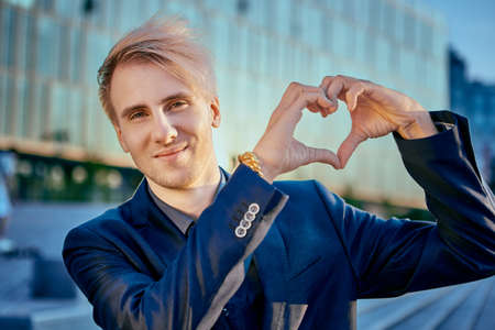 Young caucasian businessman shows heart with his hands.の写真素材