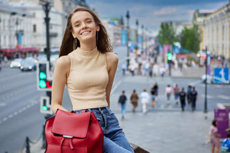 Smiling slender European woman 18 years old is resting in evening on city street.の写真素材