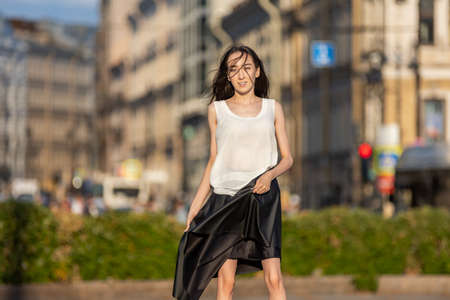 Slim brunette female in skirt walks outdoors at daytime.の写真素材