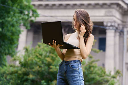 Slim caucasian woman with notebook stands in garden at daytime.の写真素材