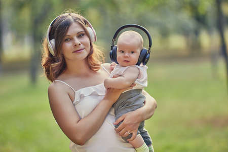 Young mother and baby boy listen to music through wireless headphones.の写真素材