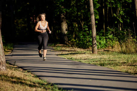 Active woman runs in public park at summer day.の写真素材