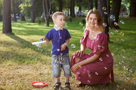 Happy woman and boy play with bobbles outdoors.