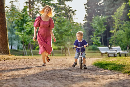 Mother and boy 3 years old on bicycle in park.の写真素材