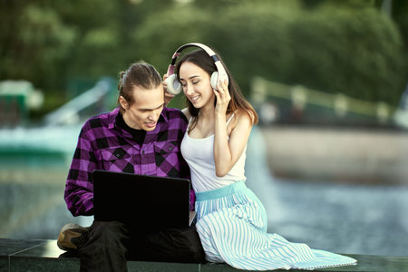 Young couple with laptop have date outdoors in summer.