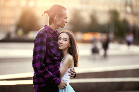 Young man hugs woman during date in park.の写真素材