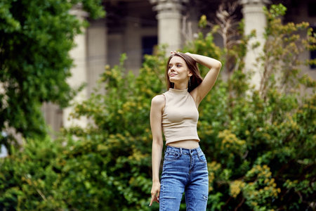 Graceful woman in jeans stands in park at daytime.の写真素材