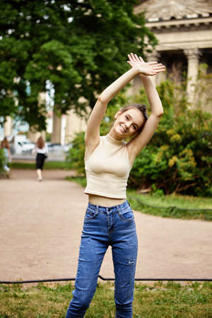 Slender young woman stand in city garden at daytime.の写真素材