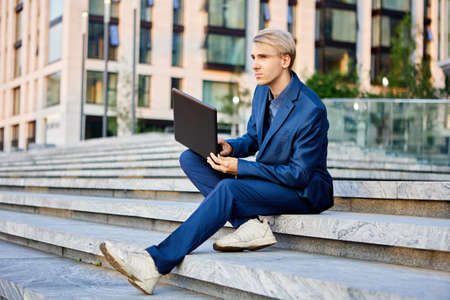 White collar with laptop sits near office building.の写真素材
