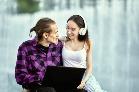 Young couple uses laptop outdoors during romantic date.