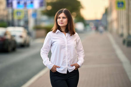 Woman 26 years old with brown hair stands on street.の写真素材
