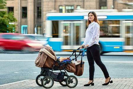 Mother with child in baby carriage walks near traffic.