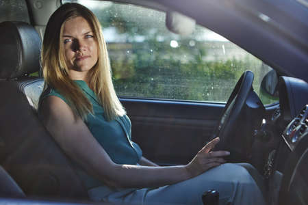 Caucasian young woman drives car in summer day.の写真素材