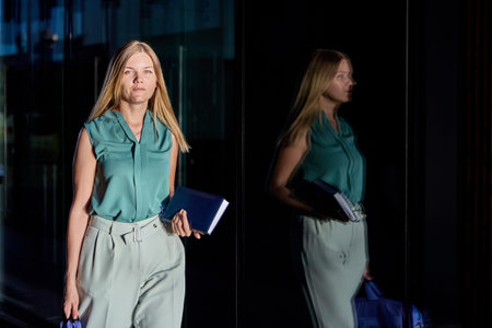 Female office worker holds notebook for notes near business center.の写真素材