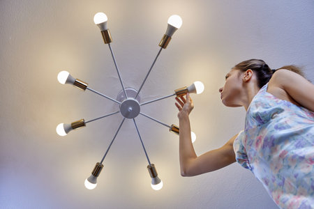 Replacing light bulb in LED lamp by woman indoors.