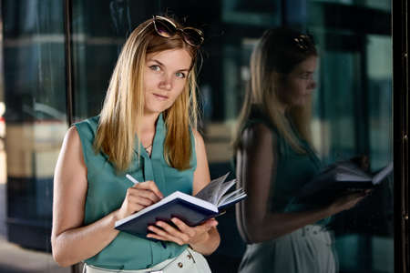 Female secretary with notebook stands near business center.の写真素材