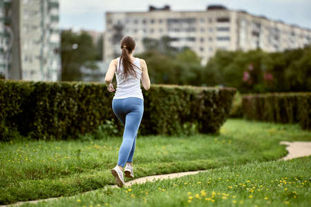 Rear view of woman jogging in city park.の写真素材