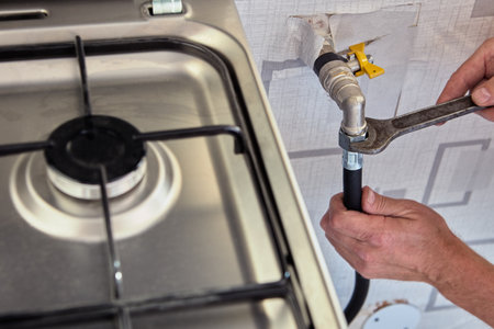 Gasman disconnects flexible hose from gas stove.の写真素材