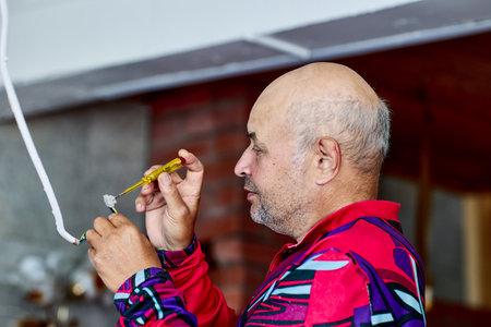 An elderly man repairs home electrical wiring.の写真素材