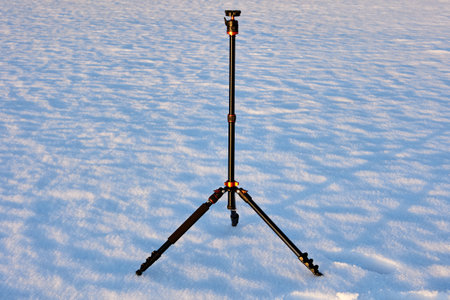Steady photo tripod on snowy crust in field in winter.の写真素材