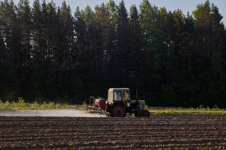Applying pesticides to potato crop using sprayer on boom mounted to an agricultural tractor.の写真素材