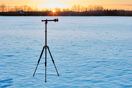 Golden hour for photography, lightweight aluminum tripod is mounted on snowy crust.の写真素材