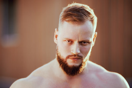 Close-up gaze of bearded European man outdoors in summer.の写真素材