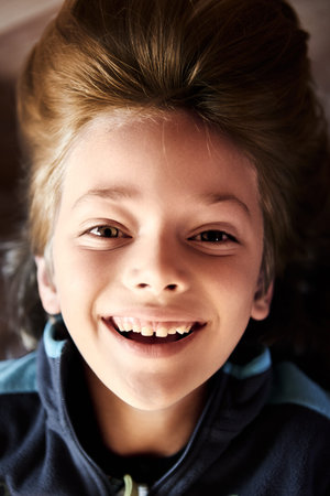 Young boy hanging upside down is smiling at camera.
