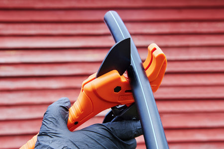 Plumber cuts HDPE pipe with pipe cutter with ratchet, when installing pipeline for drinking and...