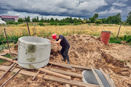 When installing septic tank made of concrete rings, worker uses roller system to move ring.の写真素材