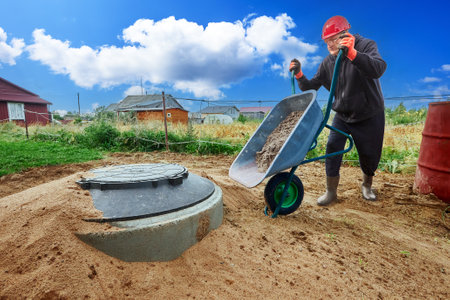 Installation of sewer system for private house in suburbs, builder delivers sand in wheelbarrow.の写真素材