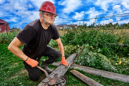 Hand manual winch with wire rope mechanism is used on suburban property by middle aged white man.の写真素材