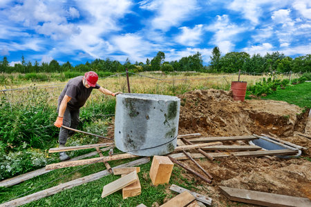 Worker uses crowbar as lever to move concrete ring along roller decking.の写真素材