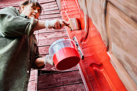 Painting door red with metal paint, female house painter using flat paintbrush.の写真素材
