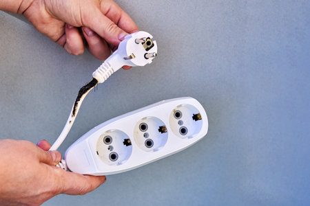 Burnt power cable with tee socket after overloading with electrical appliances.の写真素材