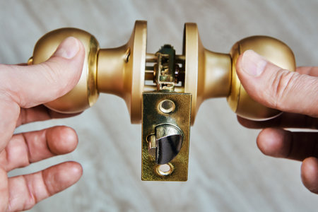 Knobset assembly shows internal components, including spindle and latch bolt, with round knob shape held against light backdrop for clarity.の写真素材
