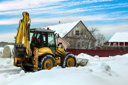 Articulated backhoe loader uses hydraulics to drive dozer blade for snow removal, while...