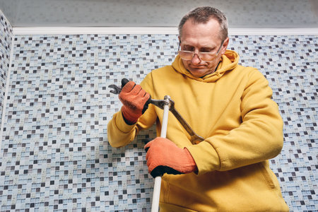 Plumber uses two open end wrenches to tighten securing nut of compression fitting onto end of multilayer pipe during installation of coupling.の写真素材