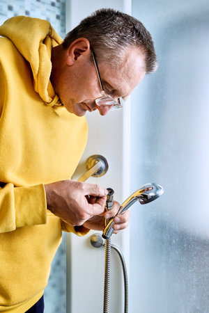 Preparing for hose replacement plumber checks sealing washer at end of shower hose due to leak in old shower connection.の写真素材