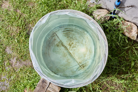 Rain barrel lined inserted into watering barrel placed in garden, top view, wide angle.