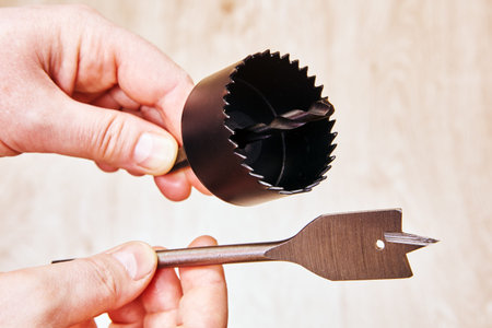 Woodworking hole saw and spade drill bit in hands ready for drilling tasks construction repair...