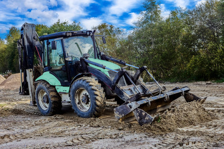 Wheel loader performs earthmoving work with sand piles visible on construction site.