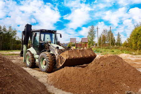 Wheel loader is on sandy ground positioned before significant sand pile, several additional piles...