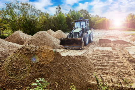 Excavator loader used for distributing and leveling sand on site.