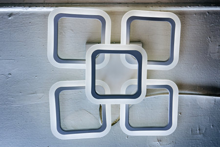 Modern LED ceiling light with four square elements, minimalist design, fixed to ceiling surface.の写真素材
