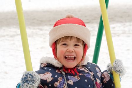 child is playing in colorful swing at the playgroundの写真素材