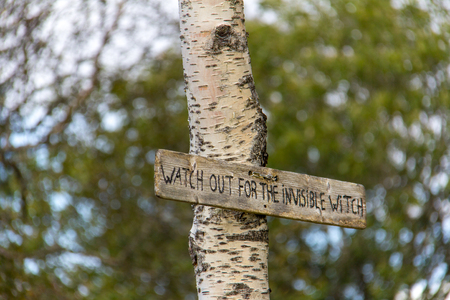 Sign found attached to a birch tree on hiking trail on Floyen mountain in Bergen, Norway. It reads Watch Out for the Invisible Witch.の写真素材