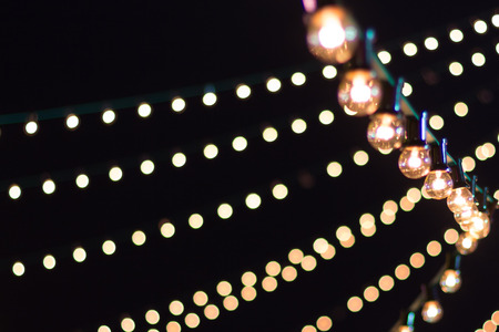 Strings of lights contrasted against a black sky at a festivalの写真素材