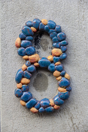 A decorative house number eight consisting of blue and orange rocks